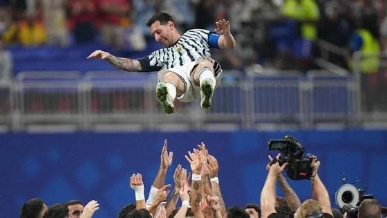 Lionel Messi in an Argentina shirt, lifted by teammates.
